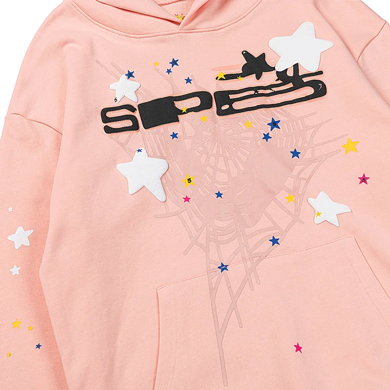 Close-up of the Sp5der Bellini hoodie in pale peach with black SP5 lettering, white puffy stars, and a faint tonal web