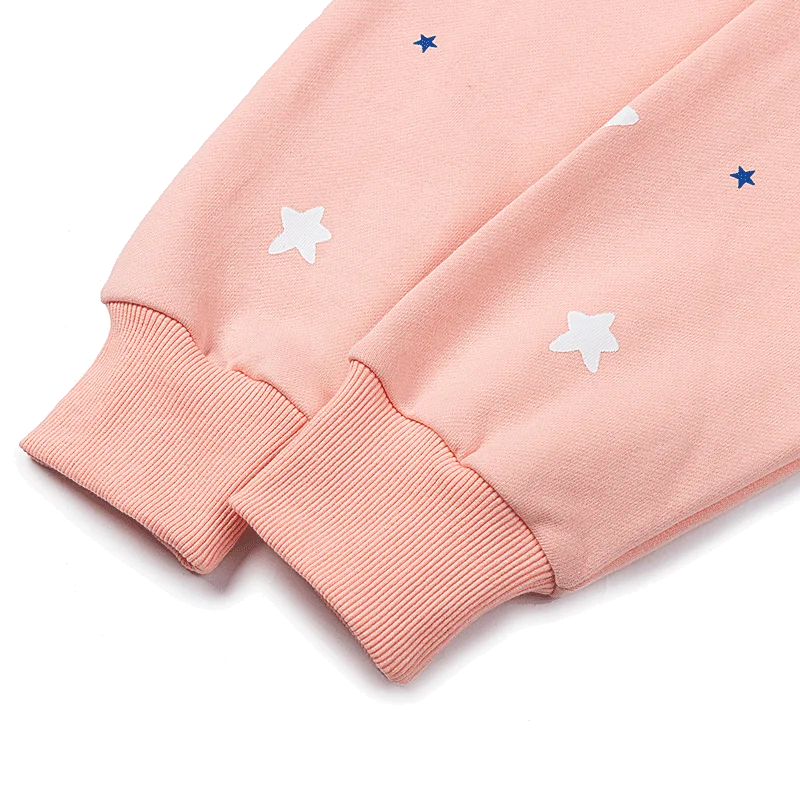 Close-up of the peach pink Sp5der Bellini hoodie sleeves, showing thick ribbed cuffs and printed white and blue stars on the fleece